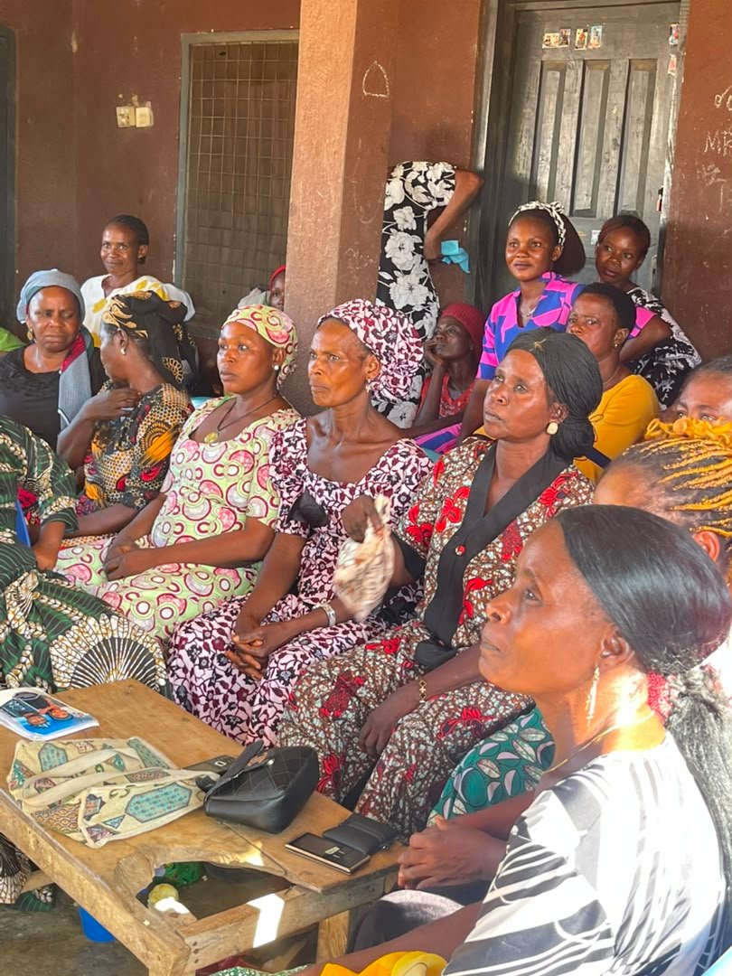 Women in head ties seated together behind a wooden table at the Ugondo meeting