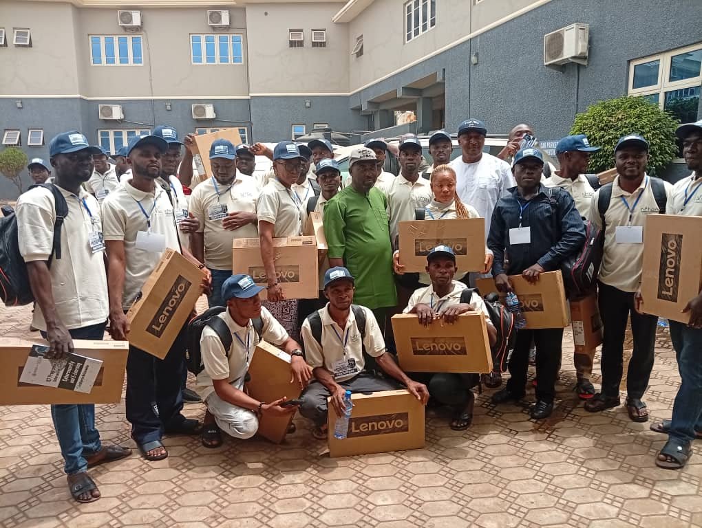 Agber in a green shirt with beneficiaries holding Lenovo laptop boxes