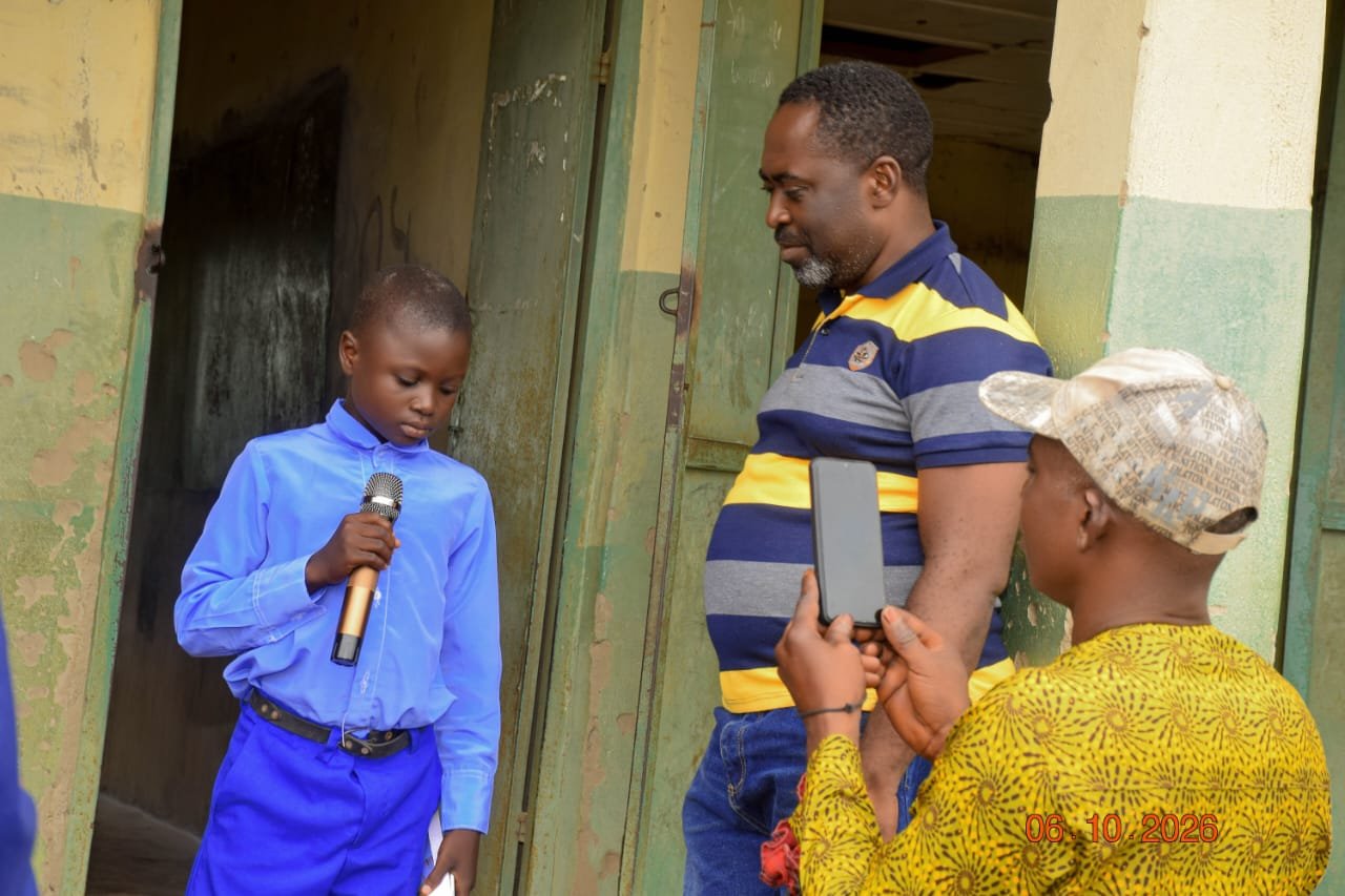A pupil speaking into a gold microphone while Agber records him on a phone